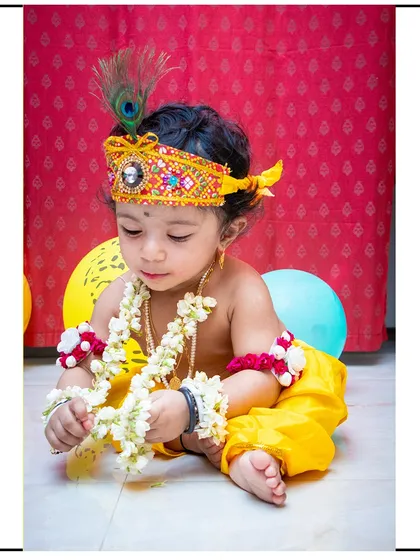 Capturing the quiet, focused moments is just as important. Here, our little Krishna is intently examining the props, creating a sweet and thoughtful portrait.
