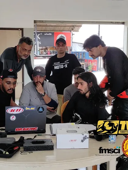 It's not just about riding, it's about getting smarter. Our team and riders huddle around a laptop, analyzing telemetry data to find those extra tenths of a second on the track.
