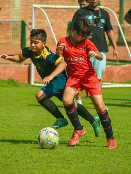 Two young players battle for possession, learning the importance of strength and determination on the field.