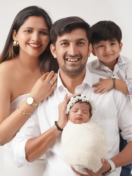 A classic family portrait with parents, a proud big brother, and the new baby sister. Everyone is smiling for the camera, creating a perfect memory to cherish.