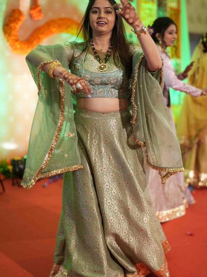 Our client looks absolutely radiant as she dances at her Mehendi ceremony. She is wearing a custom pastel green brocade lehenga with bell sleeves, designed for comfort, elegance, and movement.