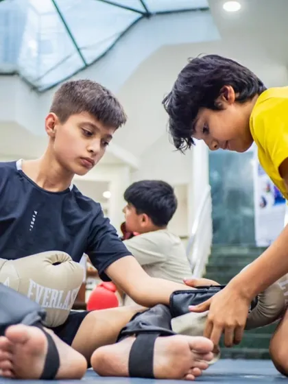 Teamwork is part of the grind. One student helps another secure his shin guards before a drill. We teach our warriors to look out for their training partners.