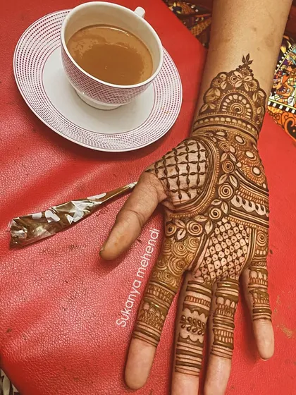 A moment of relaxation with chai and mehendi. This design features intricate check patterns and swirls, a perfect companion for a quiet afternoon.