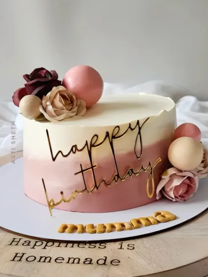 An elegant ombre cake in dusty rose tones, decorated with paper flowers and a gold "Happy Birthday" script for a mother's celebration.