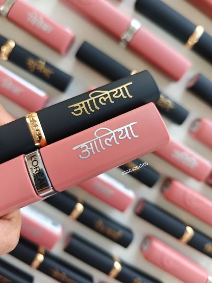 A close up of the L'Oréal lipsticks personalized for 'Alia' in Devanagari script. I used both gold and silver fills to complement the different lipstick casings, creating a beautiful and cohesive set.