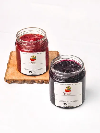 Two jars of handmade jam, one strawberry and one blueberry, styled together for a product comparison shot. The clean background is ideal for e-commerce listings.