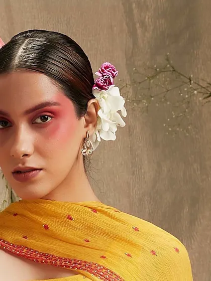 A close-up portrait with a creative blush application and flowers in the hair. This artistic approach to makeup is perfect for a bohemian or fashion-forward bride looking for a unique and memorable style.