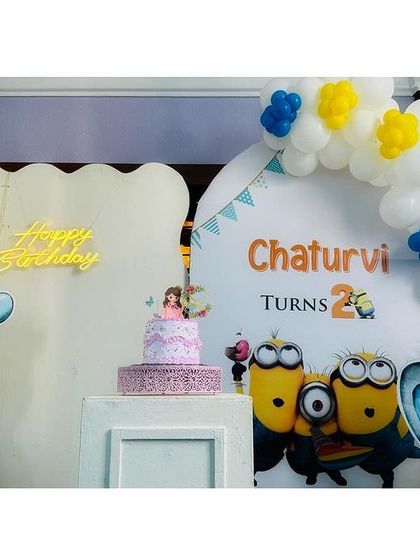 A fun and playful setup combining Dumbo and Minions for Chaturvi's second birthday. This decor features cute elephant cutouts, a Minions backdrop, and a simple white and yellow balloon arch.