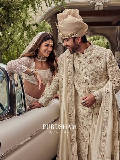 A classic love story, framed by a vintage car. The groom's embroidered sherwani and the bride's coordinated lehenga are designed to create a picture of heritage and grandeur.