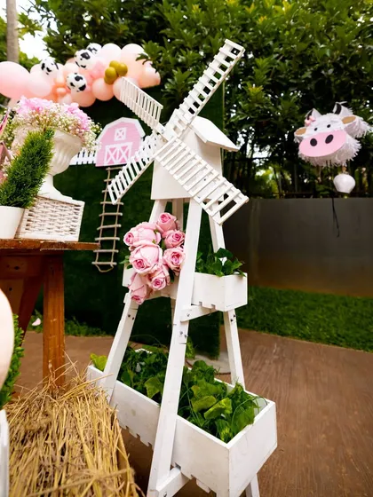 Every detail is thoughtfully designed, like this decorative white windmill that adds an authentic touch to the farm theme. It's paired with fresh flowers and greenery to enhance the rustic, charming atmosphere of the party.