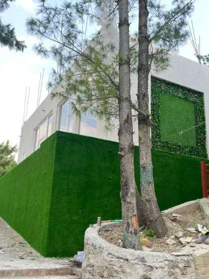 This project in Theog involved not just the framed design but also covering the entire lower wall with artificial grass, creating a seamless green look against the natural landscape.