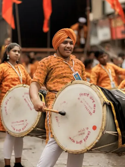 The color version of the Sikh dhol player, his orange turban matching the troupe's uniform.