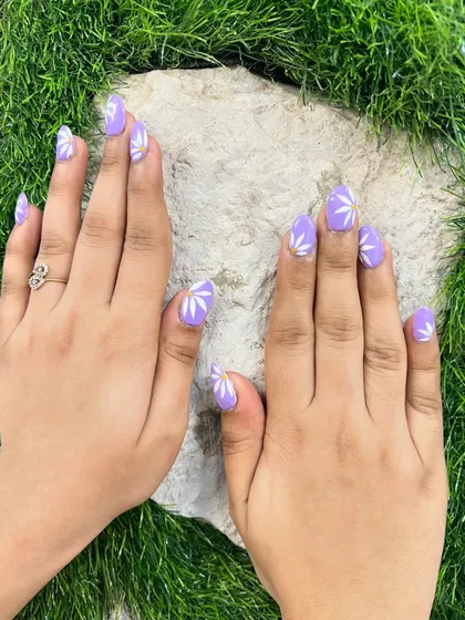 A fresh and fun design featuring a lovely lilac purple base. Each nail is adorned with a simple, hand-painted white daisy for a touch of floral charm.