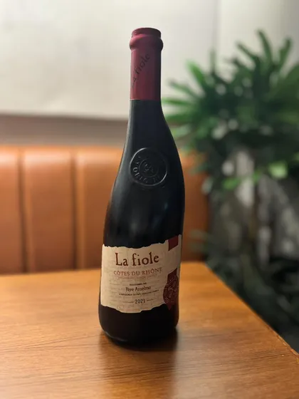 A bottle of La Fiole, a classic Côtes du Rhône from France, resting on our table. This is one of the many excellent bottles available for you to explore as part of our extended weekend hours.