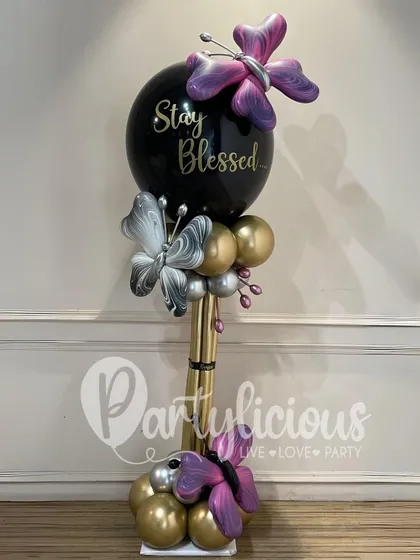 A "Stay Blessed" balloon bouquet in a chic black, gold, and silver palette. The sculpted butterflies add a touch of elegance and artistry to this beautiful arrangement.