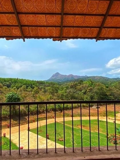 A view from a cottage balcony in Sakleshpur, looking out over the resort grounds towards the mountains.