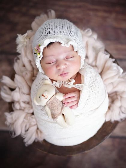 A sleeping newborn, swaddled in white and holding a tiny teddy bear. These are the sweet details I love to capture.