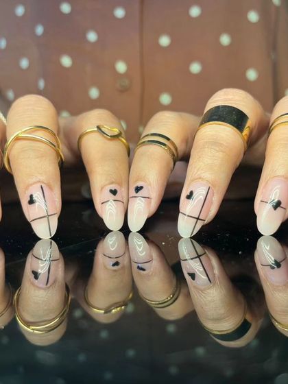 A minimalist and edgy design with fine black lines and heart shapes on long, sheer nails.