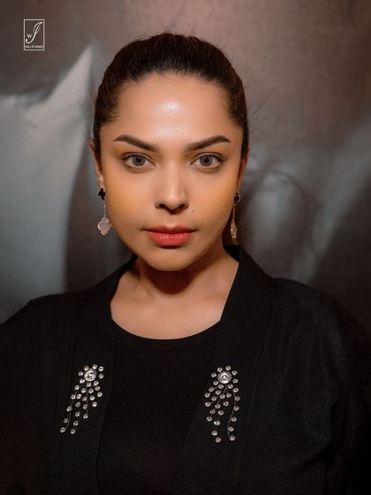 A clean and elegant beauty headshot. The lighting is soft and flattering, focusing on the model's flawless makeup and striking features.