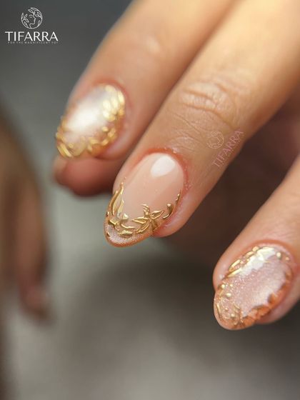 A close-up shot focusing on the delicate, hand-sculpted gold details framing a shimmering cat-eye nail.
