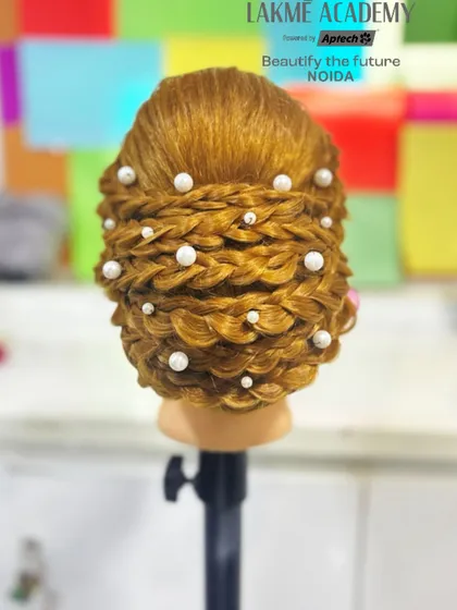 An intricate braided updo on a mannequin, adorned with pearls. We ensure students get ample practice on dummies to perfect their technique before working on live models.