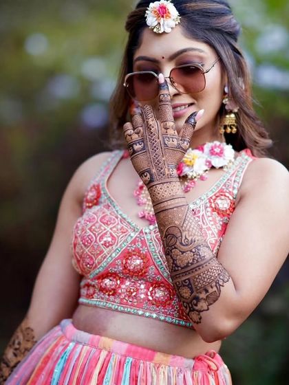 A close-up of a bride with sunglasses, her mehandi-covered hand adding to her cool vibe.