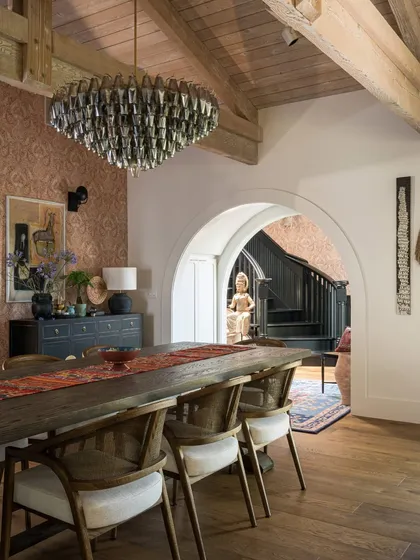 This dining area in Saratoga is defined by its dramatic chandelier and the archway that frames the view. The long wooden table is perfect for hosting, while the patterned wallpaper adds a layer of texture and sophistication to the space.