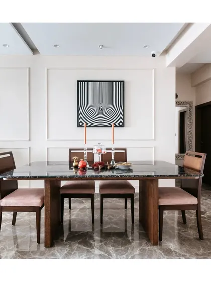 The dining area in this home is defined by its clean lines and modern aesthetic. The dark marble table, simple wooden chairs, and graphic wall art create a sophisticated space for formal and informal meals.