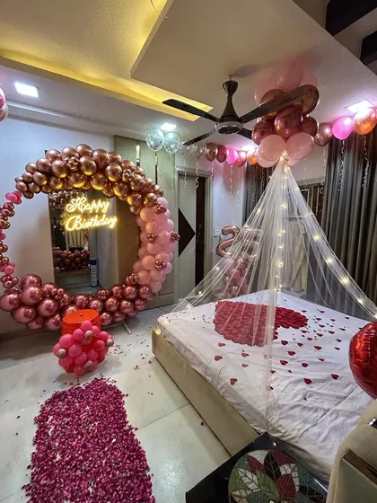 A duplicate image showing the wide view of the romantic birthday room setup, combining a balloon ring, bed canopy, and rose petals.