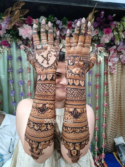 The bride proudly holding up her arms, a beautiful canvas of henna art.