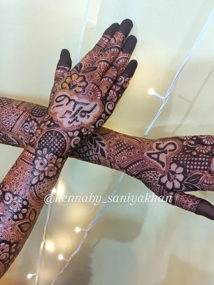 This design features the initials 'A' and 'S' on the forearms and the name 'Saddam' on the palm. A truly personalized bridal mehendi.