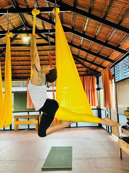 A student holds a graceful, suspended pose, demonstrating the core strength and balance she has developed in our Aerial TTC.