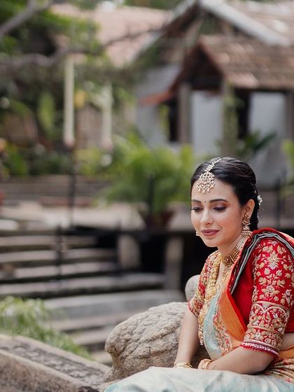 A bride sits on the edge of the stone kalyani, the tranquil water and heritage buildings creating a picturesque and peaceful backdrop.