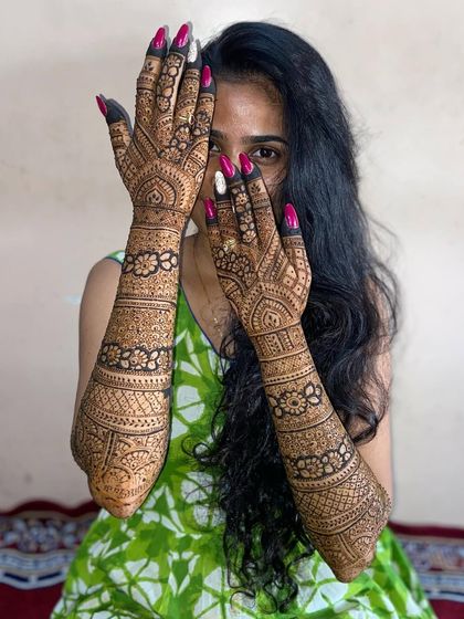 A happy client showing off her beautiful full-arm mehandi, a great option for the sister of the bride.