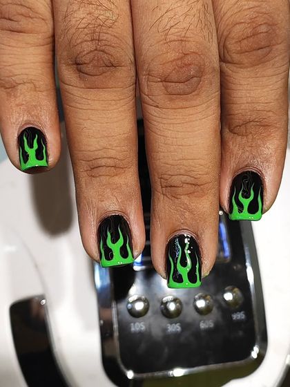 A close-up of the hand-painted neon green flames. I love doing detailed, edgy art like this on short nails to show that you don't need length to have a cool style.