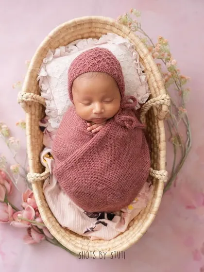 A peaceful newborn in a basket, surrounded by delicate flowers. This classic pose is always a favorite among parents.