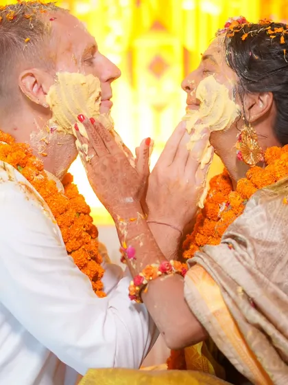 A tender moment amidst the fun. The couple gently applies haldi to each other, a sweet contrast to the usual chaos of the ceremony.