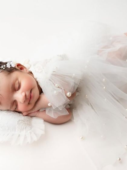 The most gorgeous sleeping beauty. Dressed in a delicate white tulle outfit, this baby looks like a tiny angel, captured against a clean, simple background.