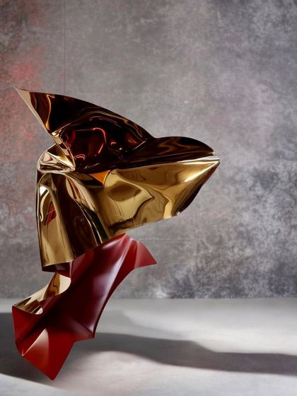 Another view of the red and gold tabletop sculpture, showing how its form creates beautiful shadows.