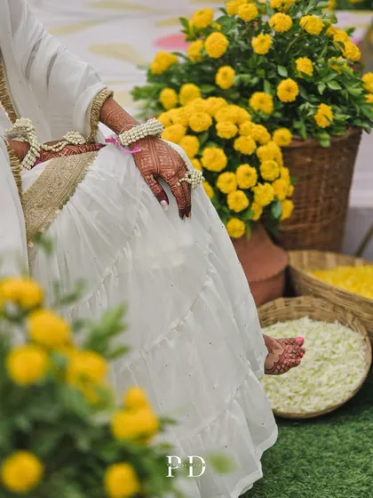 A candid shot of the bride during her Haldi ceremony, surrounded by baskets of fresh marigolds. The decor creates a perfect, vibrant setting for these joyful moments.