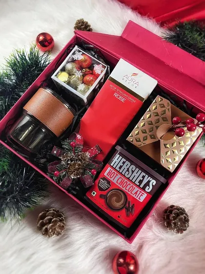 The 'Holiday Cheer' gift box is a gender-neutral option perfect for everyone. It contains Hershey's hot chocolate, a stylish mug, and other festive goodies in a vibrant red box.