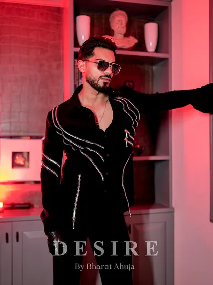 Leaning against a wall under a red light, this shot captures the moody and sophisticated vibe of the zipper-detailed shirt.