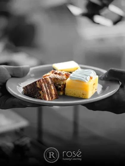 A plate of assorted mini desserts being served. This black and white shot with a pop of color highlights our philosophy of transforming moments into timeless memories through elegance and exquisite flavors.