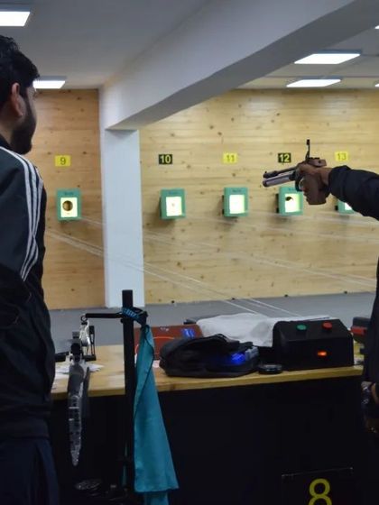 One-on-one coaching is a cornerstone of our method. Here, a coach provides real-time feedback to a pistol shooter, helping him refine his aim and stance.