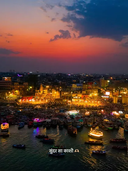 The city of Kashi, or Varanasi, glows with a spiritual energy as dusk settles over the Ganga. This aerial view captures the scale of devotion, with countless boats and people gathered for the evening aarti.