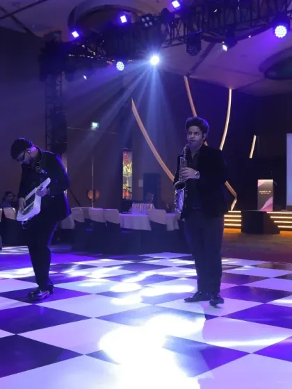 Our team of musicians, including a violinist and keytarist, performing a flashmob on a checkered dance floor during a corporate party.
