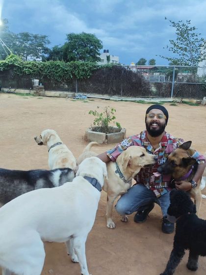 A visitor happily kneels down, completely surrounded by a circle of curious and friendly dogs of all breeds.
