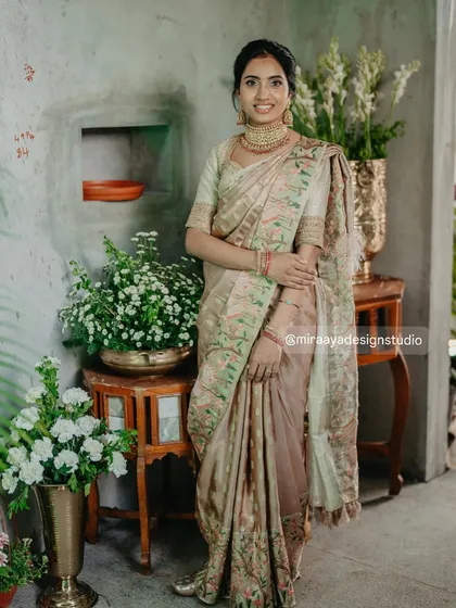 A full-length shot of a client in her custom outfit. The soft, earthy tones of the saree and blouse create a sophisticated and understated look.