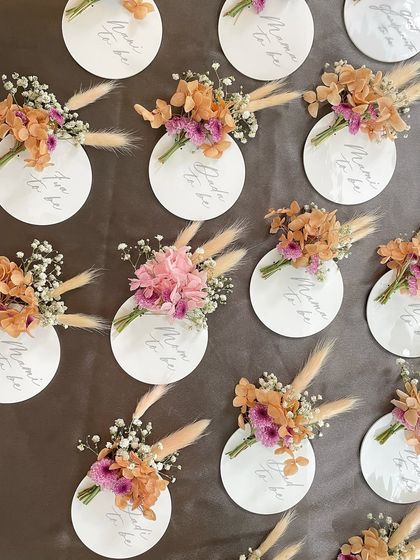 A full set of the floral name tags, showing the variety in the small bouquets for each guest, including tags for the 'Mama to be' and 'Fui to be'.