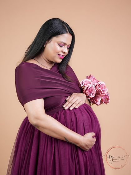 A beautiful close-up portrait of a mom-to-be holding a bouquet of pink roses. Her gentle expression perfectly captures the tenderness of this time.